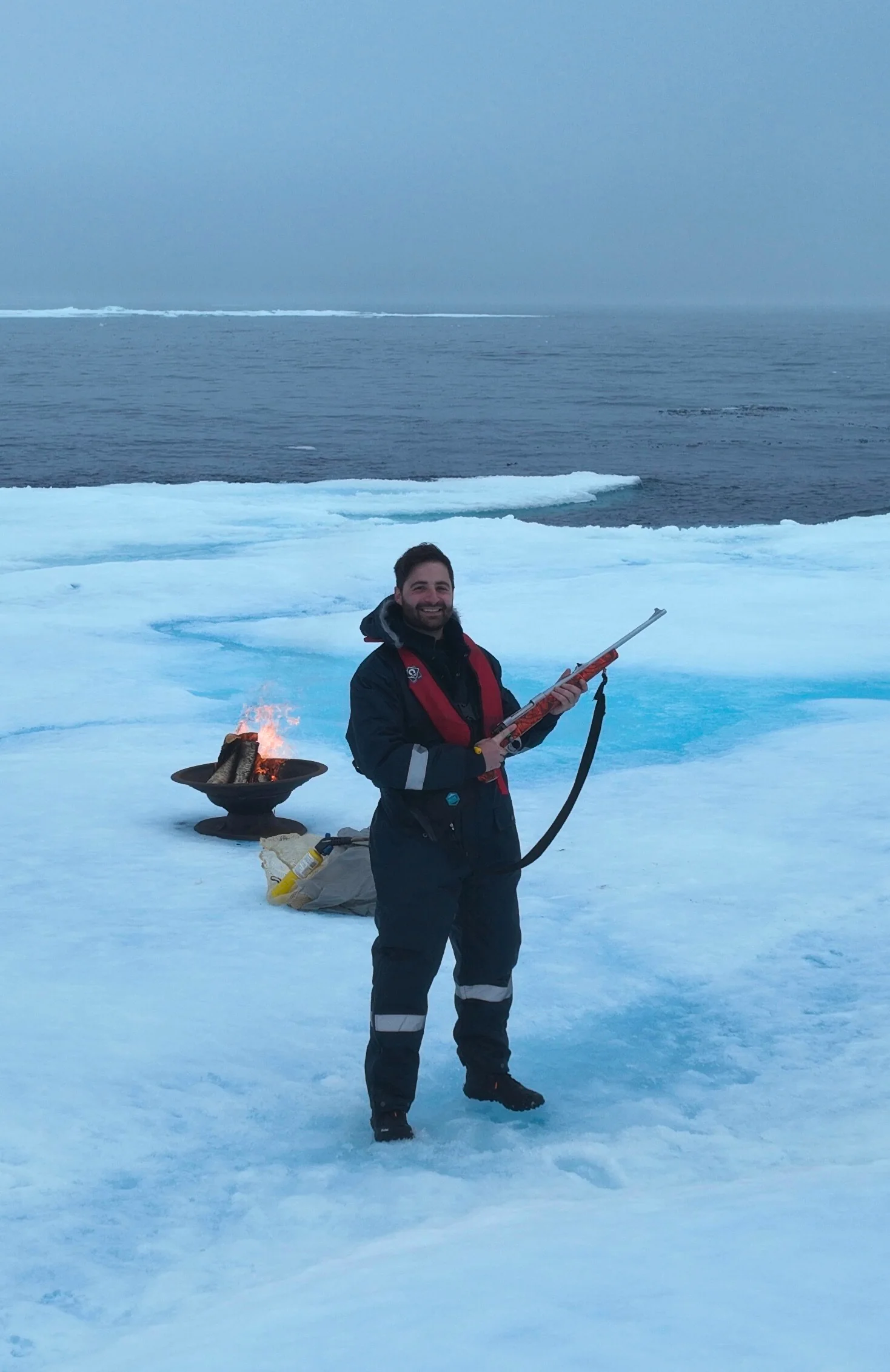 Captain Pavlos standing on the North Polar ice pack beside a fire bowl