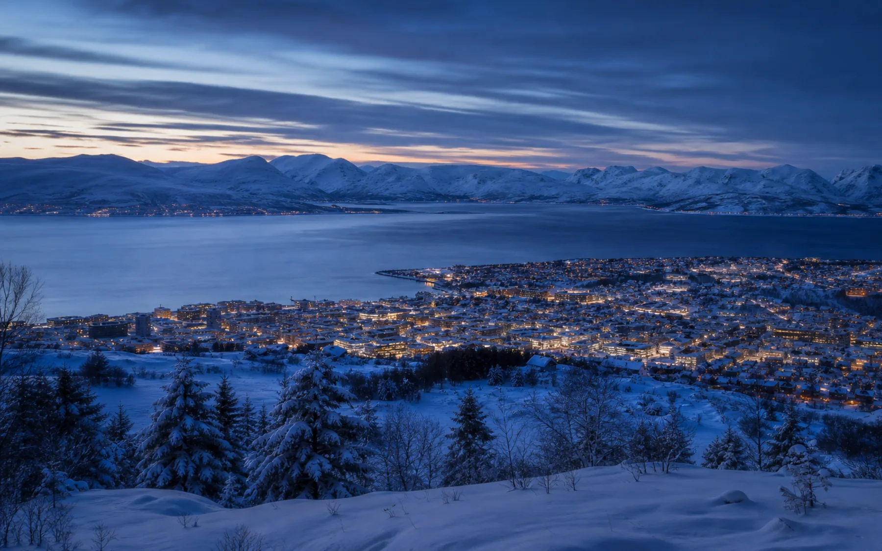 Snow-covered Tromsø beneath the mountains at Arctic blue hour